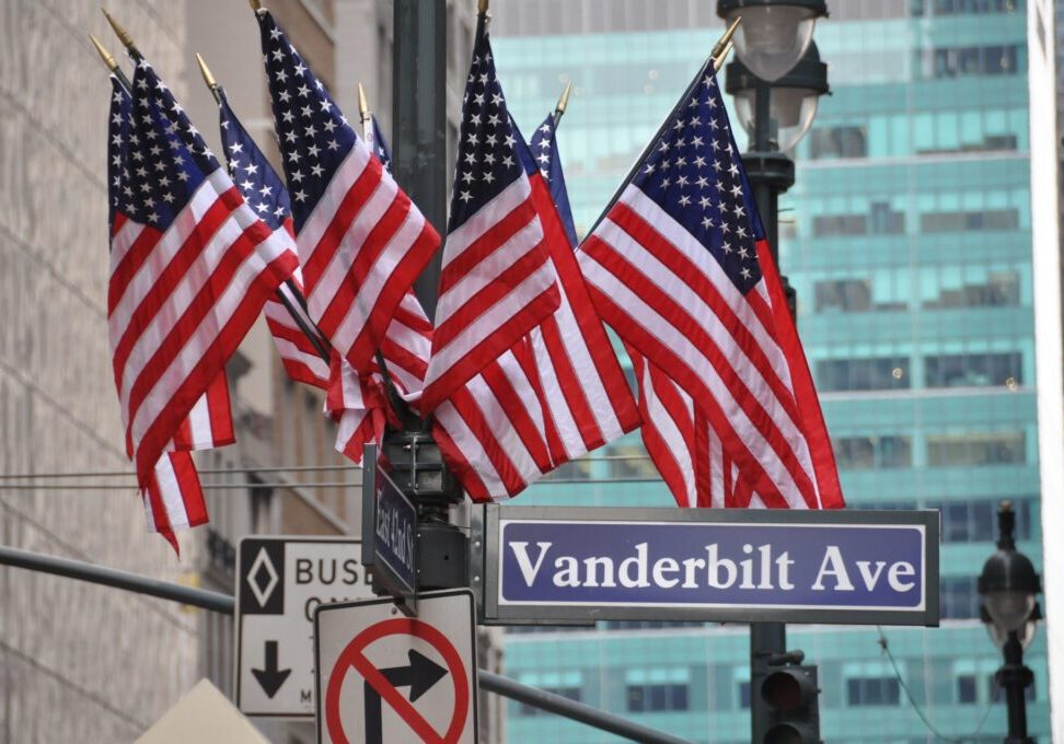 A bunch of american flags hanging on the side of a street.